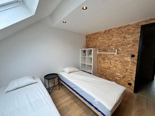 two beds in a room with a stone wall at Domaine de Hurlevent - Gite 10 personnes - Le Refuge in Aywaille
