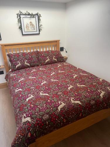a bed with a red bedspread with horses on it at Tawny Lodge, Evesham Nr Cotswolds in Evesham