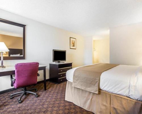 a hotel room with a bed and a desk with a computer at Quality Inn & Suites Coliseum in Greensboro