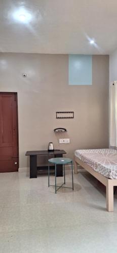 ein Zimmer mit einem Bett und einem Tisch darin in der Unterkunft Pearl farmstay in Kushālnagar