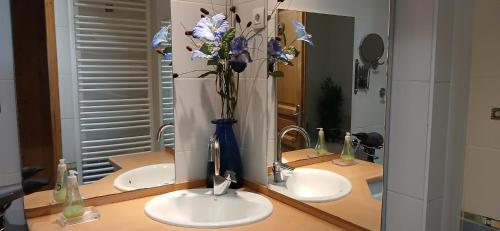 ein Badezimmer mit zwei Waschbecken und einer Vase mit Blumen darin in der Unterkunft Appartement les Coquelicots Super Besse in Besse-et-Saint-Anastaise