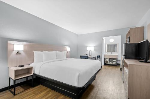 a hotel room with a large bed and a flat screen tv at Suburban Studios Daytona Beach - Speedway in Daytona Beach