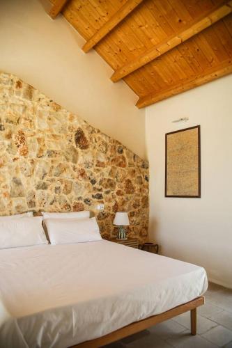 a bedroom with a bed with a stone wall at Masseria Voluzzi in Copertino