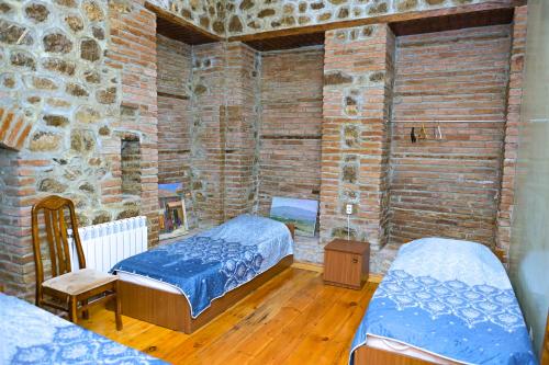 a bedroom with two beds and a brick wall at Ilham Mustafa Houses in Sheki