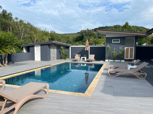 a swimming pool with lounge chairs and a house at Kongsai Private poolvilla in Klong Khong in Ko Lanta Yai