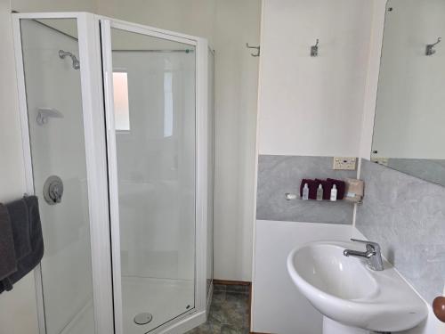 ein weißes Badezimmer mit Dusche und Waschbecken in der Unterkunft Palmcourt Motel in Westport