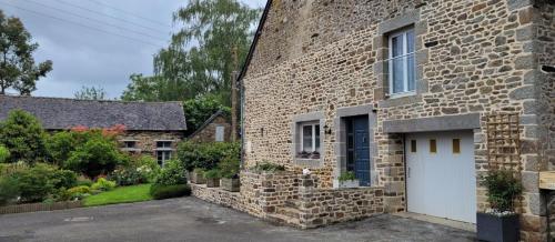 een stenen huis met een witte deur in een tuin bij Chambre D'hôtes De La Gandonnière in La Duchaie