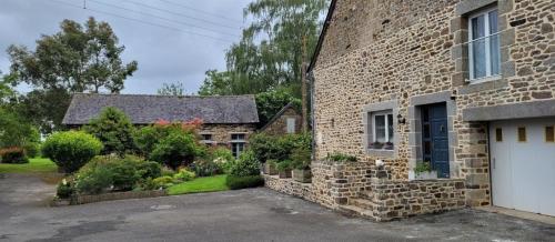 een stenen huis met een witte garage ervoor bij Chambre D'hôtes De La Gandonnière in La Duchaie