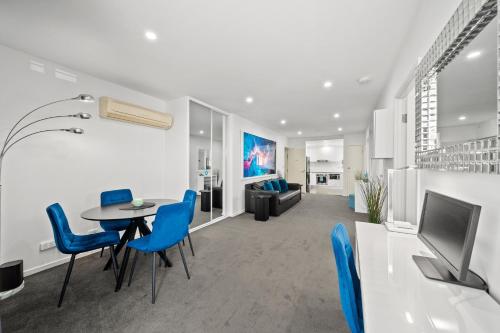 a living room with a table and blue chairs at 2BR Apt Gungahlin Square Luxe Super Central Wifi Wine Secure Parking in Canberra