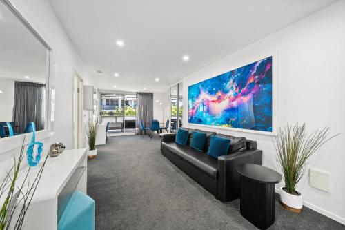 a living room with a black couch and blue pillows at 2BR Apt Gungahlin Square Luxe Super Central Wifi Wine Secure Parking in Canberra