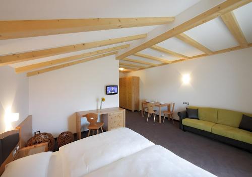 Col di VillaResidence Alpenrose的一间卧室，里面有一张床、一张桌子和一张沙发