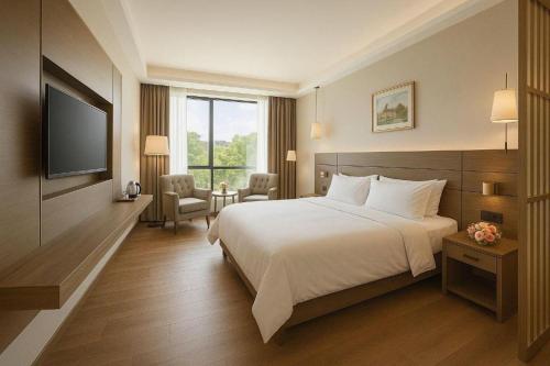 ein Hotelzimmer mit Bett und Fernseher in der Unterkunft Hanyong Hotel Shenzhen International Exhibition Center in Fenghuangwei