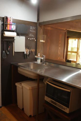 eine Küche mit Spüle und Mikrowelle in der Unterkunft BoBuchi in Ichihara