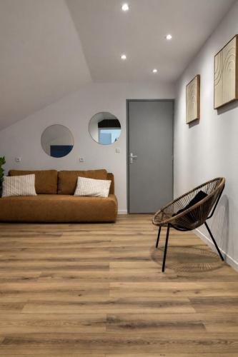 a living room with a couch and a chair at Appart Hotel 23 - Le Cocon Creusois 2 in Guéret
