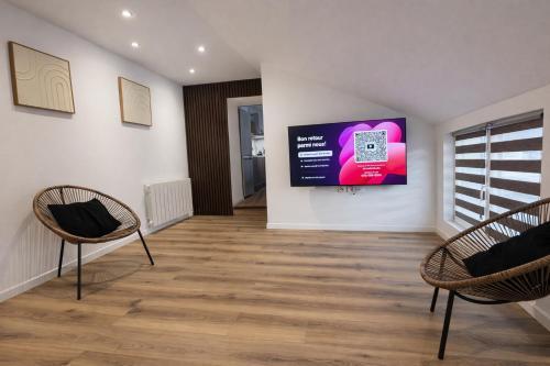 een kamer met twee stoelen en een scherm aan de muur bij Appart Hotel 23 - Le Cocon Creusois 2 in Guéret