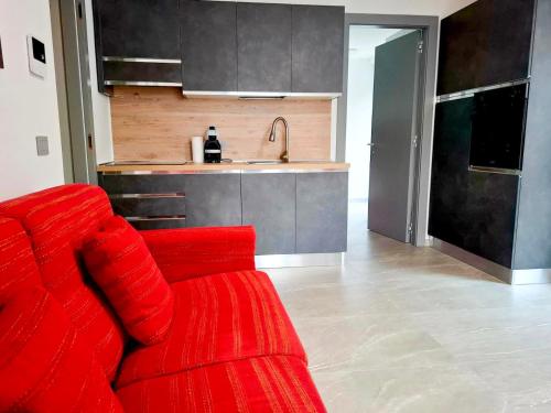 un divano rosso in un soggiorno con cucina di Casa da Normi a Valdisotto