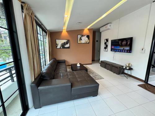 a living room with a leather couch and a tv at Naiyang Discovery Beach Resort in Nai Yang Beach
