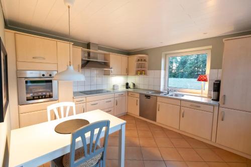 a kitchen with white cabinets and a table and chairs at Ferienwohnung Captains Lodge Steinbergkirche in Steinbergkirche