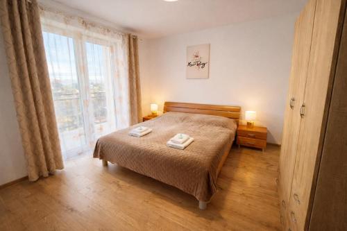a bedroom with a bed and a large window at Modern Smart Apartment, Garage & City View in Lipany