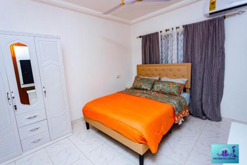 una camera da letto con un letto con una coperta arancione di Ernest homes a Kwabenyan