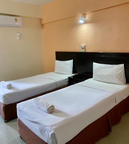 zwei Betten in einem Hotelzimmer mit weißer Bettwäsche in der Unterkunft Centerpoint Hotel in Trang