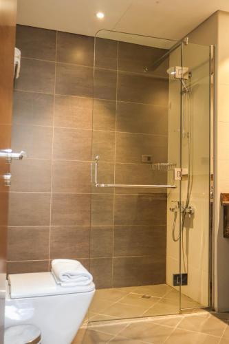a bathroom with a toilet and a glass shower at Al Riyadh Hotel Apartments in Abu Dhabi