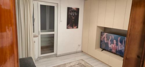 un soggiorno con TV a schermo piatto accanto a una finestra di E&A apartments a Târgu-Mureş