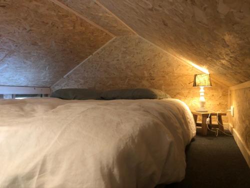 a bedroom with a large white bed in a stone wall at Domaine de Hurlevent - Tiny House petite maison écologique in Aywaille
