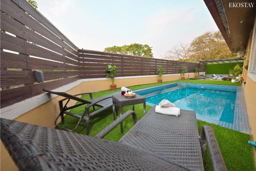 a swimming pool with a table and chairs next to it at EKOSTAY - Pinewood Villa in Alibaug