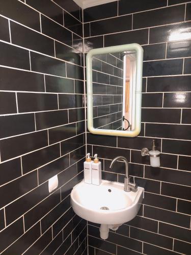 a black tiled bathroom with a sink and a mirror at Тиха гавань в чарівному містечку in Korsun'-Shevchenkivs'kyy