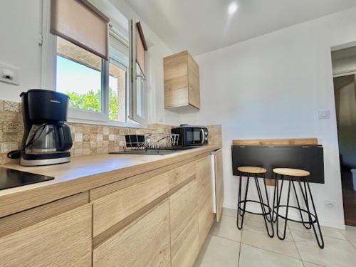 een keuken met 2 barkrukken en een aanrecht bij Occitemps in Saint Julien Les Rosiers