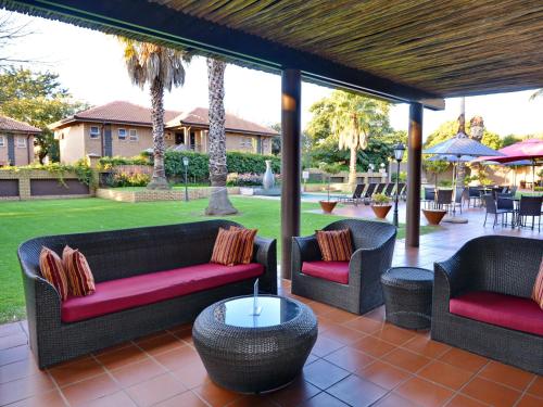a patio with two couches and a table and chairs at ANEW Hotel Witbank Emalahleni in eMalahleni