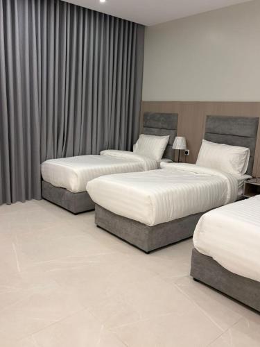a hotel room with three beds in a room at luxury royal apartments in Taif