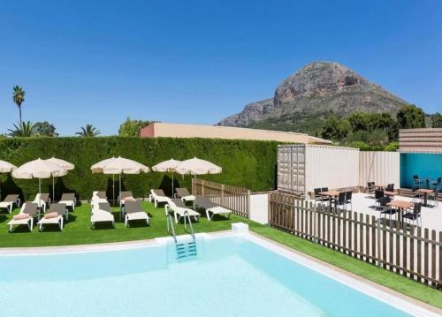 ein Pool mit Stühlen und Sonnenschirmen neben einem Resort in der Unterkunft Hotel Xabina Javea in Jávea