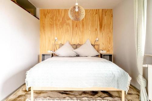 a bedroom with a white bed with a wooden headboard at Ausblick Maisenbach in Bad Liebenzell