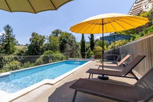ein Regenschirm und ein Stuhl neben einem Pool in der Unterkunft La grange du paris in Saint-Pierre-dʼAlvey