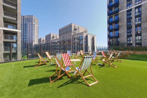 a row of chairs and tables on a field of grass at The Robinson at Wembley - Modern and Eclectic in London