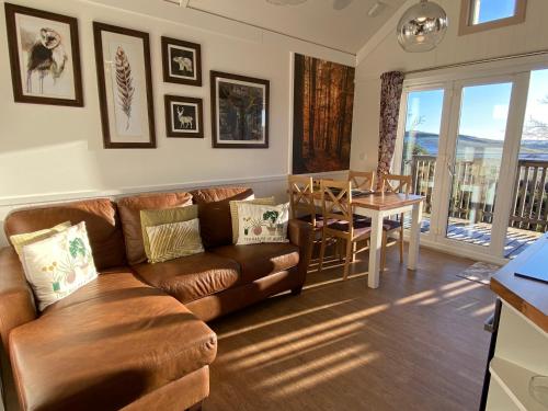 a living room with a brown couch and a table at Badger Lodge with Hot Tub in Cupar