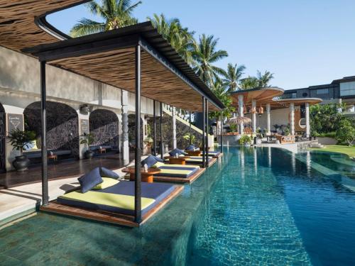 a pool at a resort with a row of beds at Soulshine Resort Ubud, Bali in Ubud