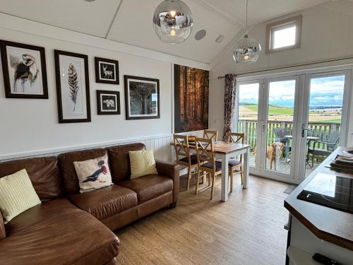 a living room with a couch and a table at Hare Lodge with Hot Tub in Cupar