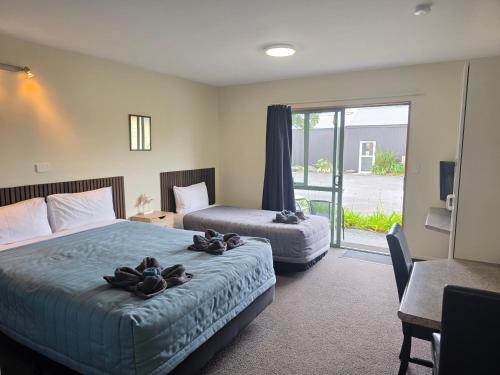 ein Hotelzimmer mit zwei Betten und Balkon in der Unterkunft Palmcourt Motel in Westport