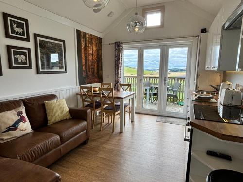a living room with a couch and a table at Hedgehog Lodge with Hot Tub in Cupar