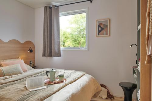 a bedroom with a bed with a laptop and a window at Camping O'Aka in Leyme