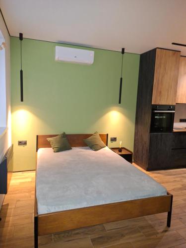 ein Schlafzimmer mit einem Bett und einer grünen Wand in der Unterkunft Green house в центрі міста in Irpin