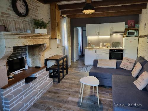 un soggiorno con divano e camino di Le Gite Aïdan a La Puye