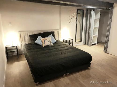 una camera da letto con un grande letto nero con due cuscini di Le Gite Leiloo a La Puye