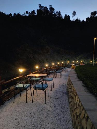 eine Reihe von Tischen und Stühlen am Strand in der Nacht in der Unterkunft Nature Camp in Nainital