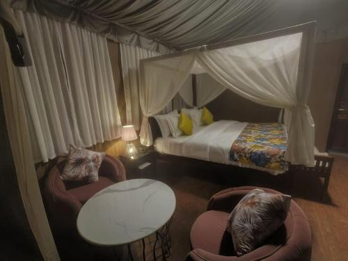 1 Schlafzimmer mit einem Himmelbett und 2 Stühlen in der Unterkunft Nature Camp in Nainital