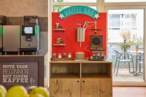 a coffee shop with a sign on a red wall at ibis Hotel Düsseldorf Hauptbahnhof in Düsseldorf