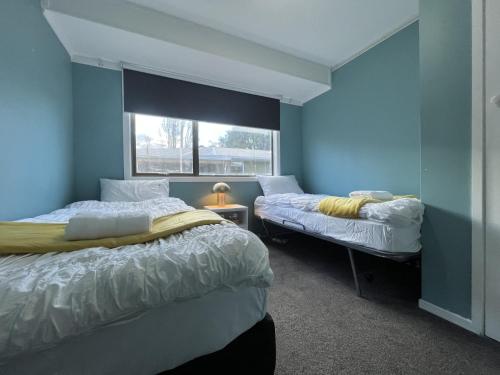 um quarto azul com duas camas e uma janela em The Sweet Pea- Room 4 em Hamilton